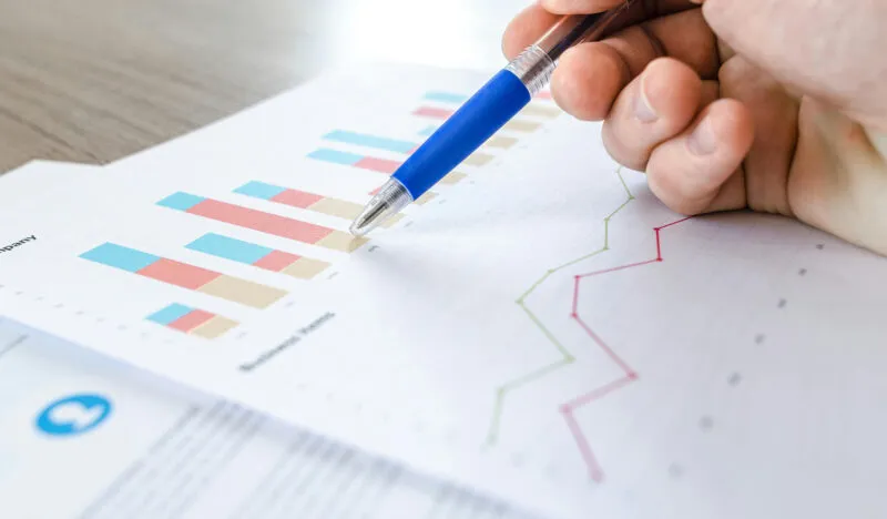 Hand met pen bij grafieken van marketingresultaten