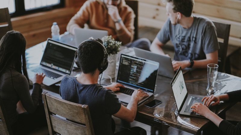 Marketingteam werkt samen achter laptops aan een tafel