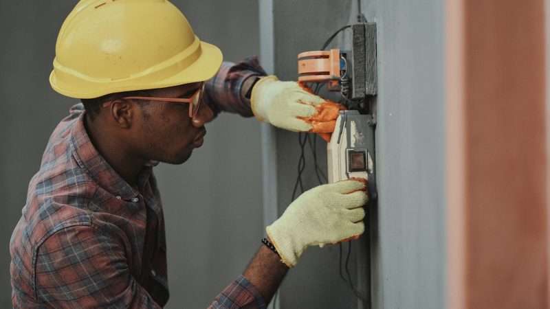 Installateur met veiligheidshelm monteert een elektrische aansluiting