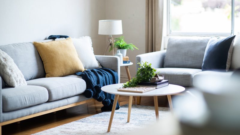 Lichte woonkamer met grijze banken en een ronde salontafel