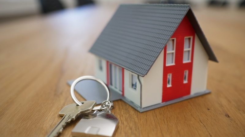 Modelhuis met huissleutels op een houten tafel