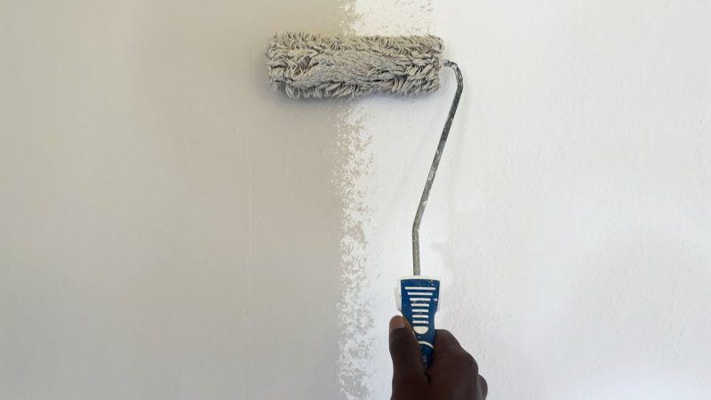 Schilder rolt met een verfroller een muur wit