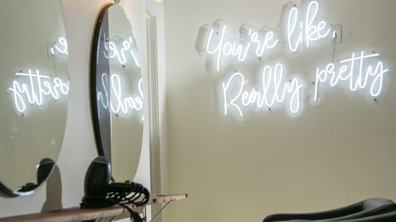 Schoonheidssalon met spiegels en een neonbord aan de muur