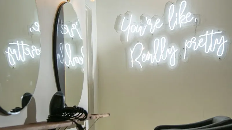 Schoonheidssalon met spiegels en een neonbord aan de muur