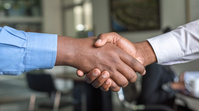 Twee mensen geven elkaar een hand na een sollicitatiegesprek