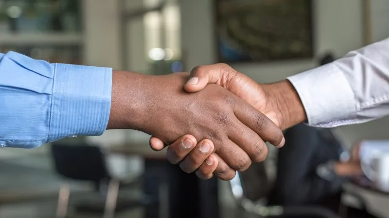Twee mensen geven elkaar een hand na een sollicitatiegesprek