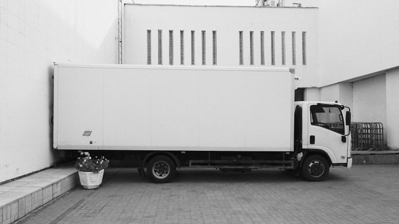 Witte verhuiswagen geparkeerd voor een gebouw