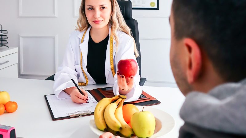 Diëtist in gesprek met een cliënt, met fruit op het bureau