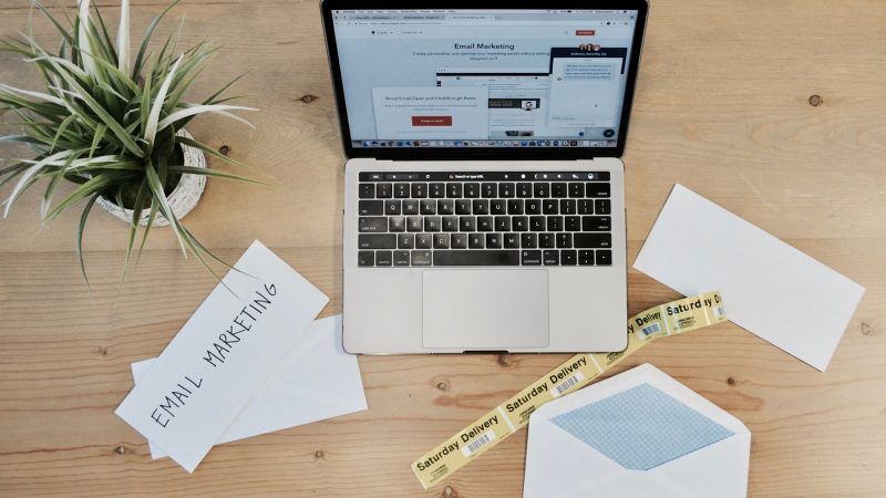 Laptop met een e-mailmarketingprogramma op het scherm en enveloppen ernaast