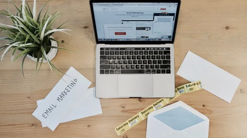 Laptop met een e-mailmarketingprogramma op het scherm en enveloppen ernaast