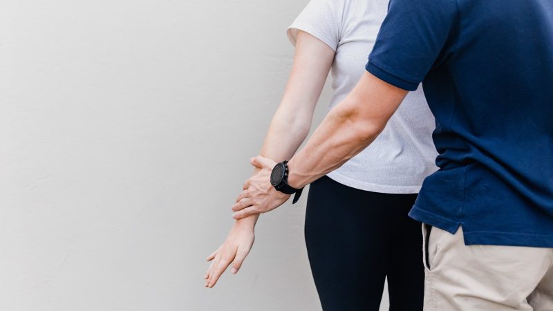 Therapeut begeleidt de armbeweging van een cliënt