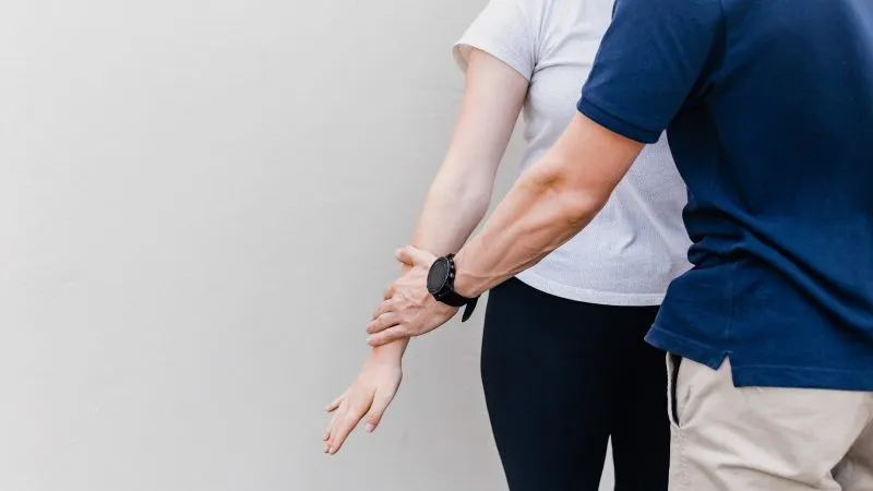 Therapeut begeleidt de armbeweging van een cliënt
