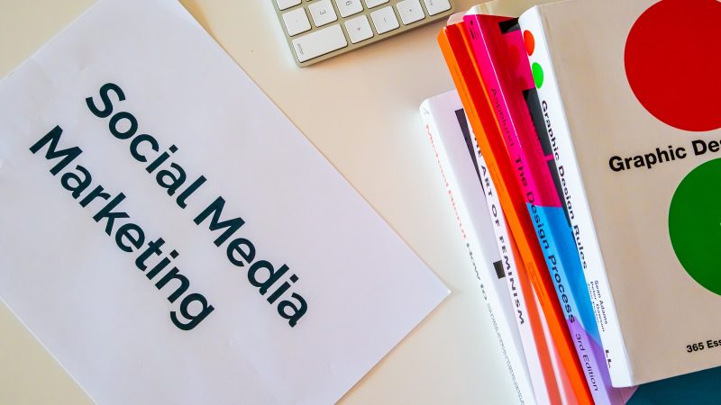 Vel papier met de tekst Social Media Marketing naast een toetsenbord en boeken