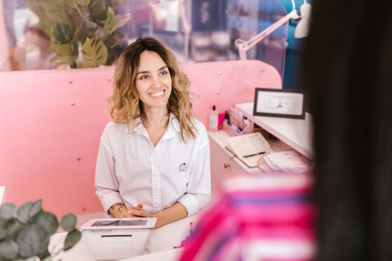Website laten maken schoonheidssalon: medewerker aan de balie met afsprakenboek en tablet