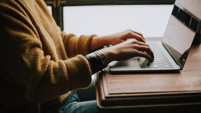 Persoon bedient een laptop met het toetsenbord