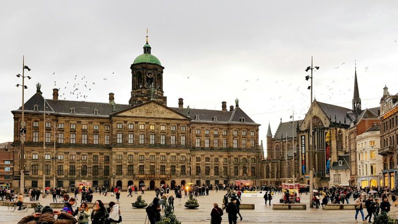 Mensen op de Dam voor het Paleis op de Dam in Amsterdam